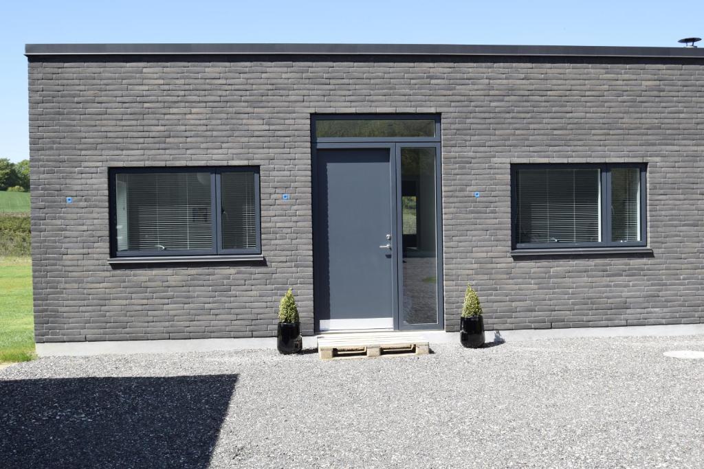 a brick building with a blue door and two plants at Fredensholm Annex in Skanderborg