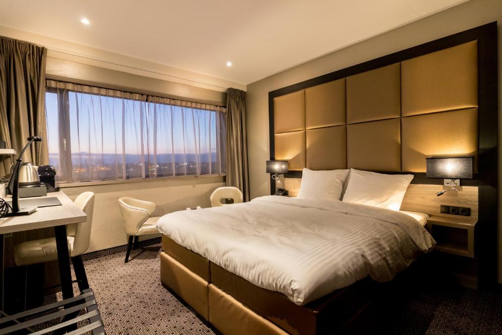 una camera d'albergo con letto, scrivania e finestra di Riva hotel Den Haag - Delft a L'Aia
