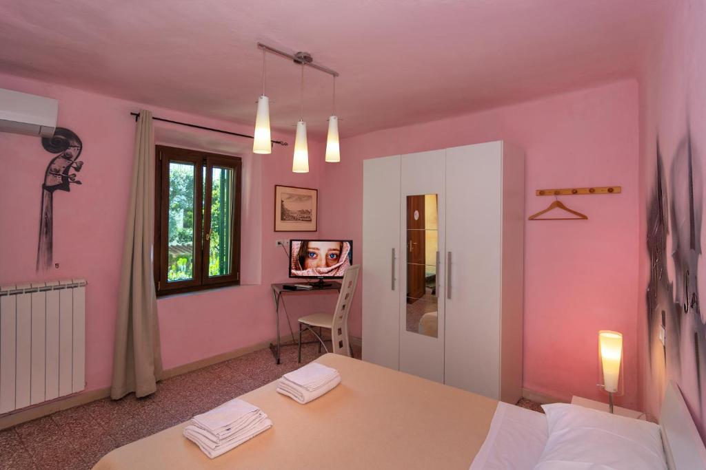 Habitación con paredes de color rosa, mesa y TV. en Maison Dei Miracoli, en Pisa