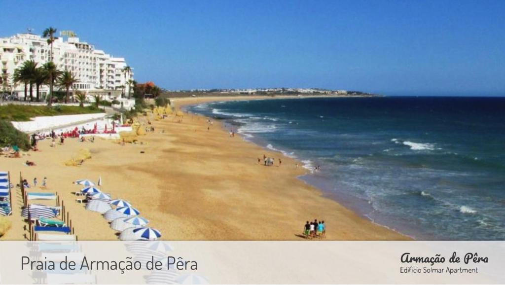 una spiaggia con ombrelloni e persone di Edificio Solmar Apartment ad Armação de Pêra