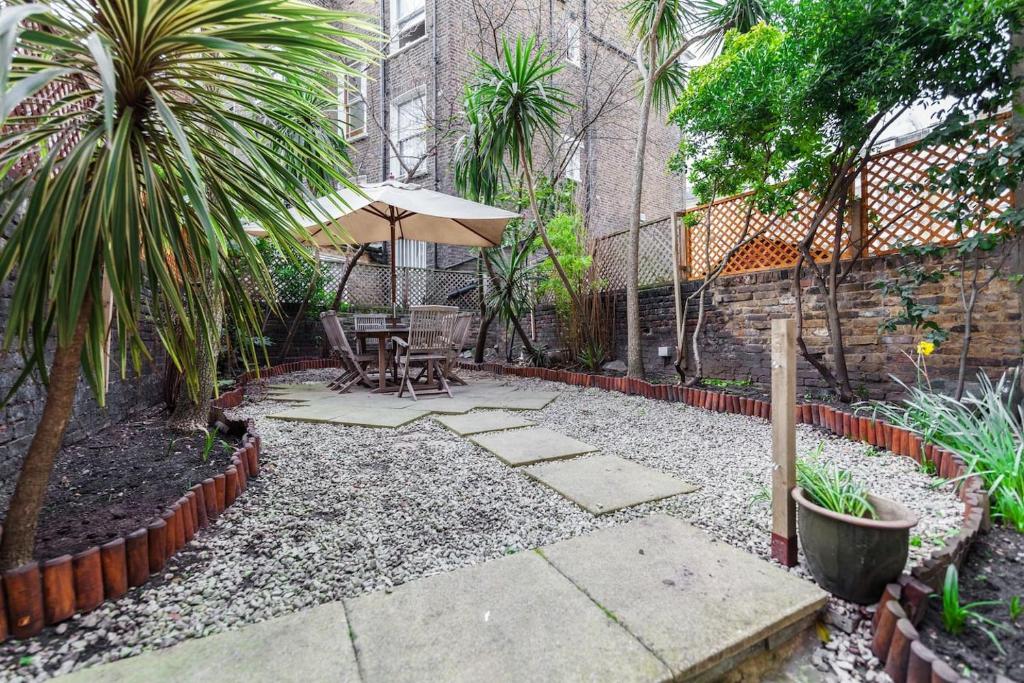 a patio with a table and umbrella in a courtyard at 3 Bedroom Garden Flat - Central Location in London