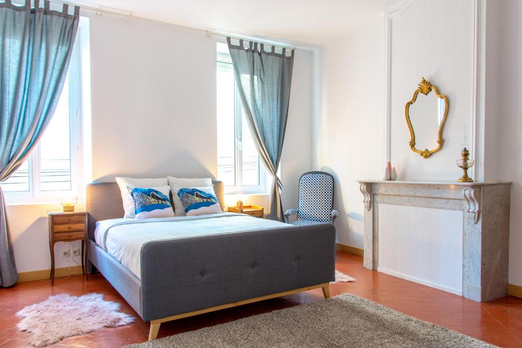 1 dormitorio con 1 cama con cortinas azules y espejo en Entre Midi - Maison d'Hôtes - B&B, en Capestang