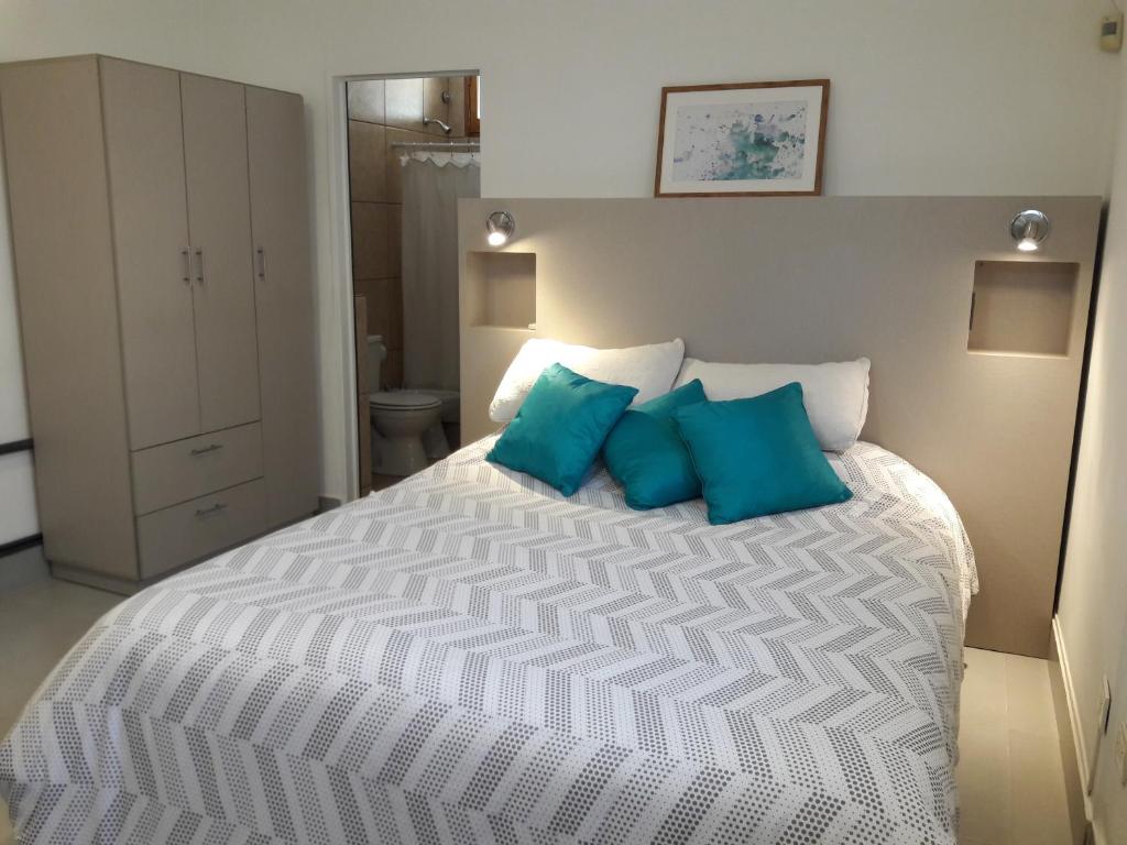 1 dormitorio con 1 cama blanca grande con almohadas azules en Apart Camilo en Mendoza