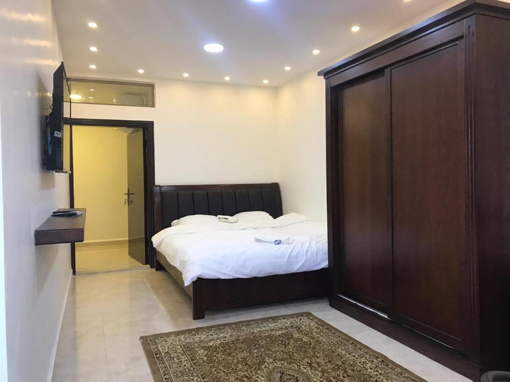 a bedroom with a bed and a large wooden closet at Sultan Home in Wadi Musa