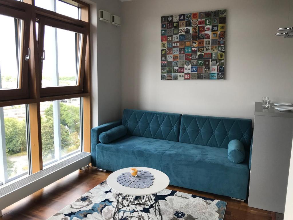 een woonkamer met een blauwe bank en een tafel bij Dworzec Gdański Apartament in Warschau