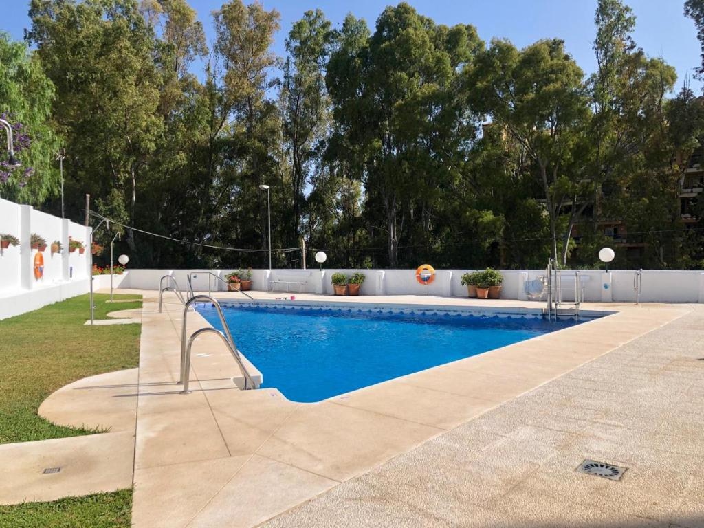 een zwembad in een tuin met bomen op de achtergrond bij Studio Orquídea Beach 4 in Fuengirola