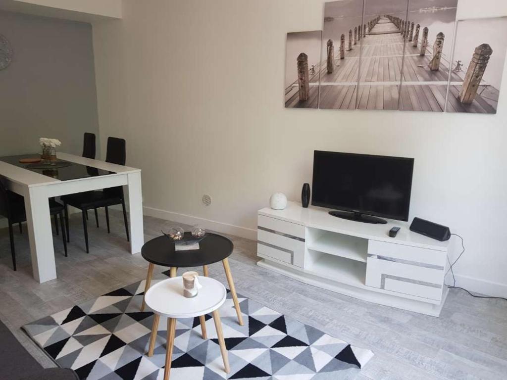 ein Wohnzimmer mit einem TV, einem Tisch und einem Tisch in der Unterkunft Le cosy d’Amboise in Amboise
