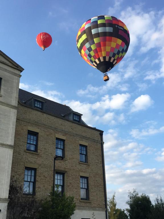 dois balões de ar quente sobrevoando um edifício em Upton Country Park Guest House em Northampton