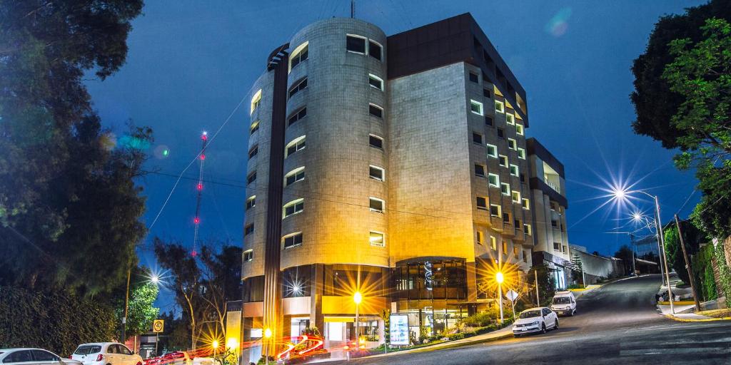 Un palazzo alto in una strada di città di notte di JF Grand Puebla a Puebla