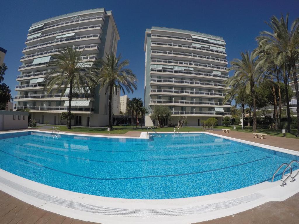 a large swimming pool in front of two buildings at Apartamento La Florida en Playa de Gandía in Playa de Gandia