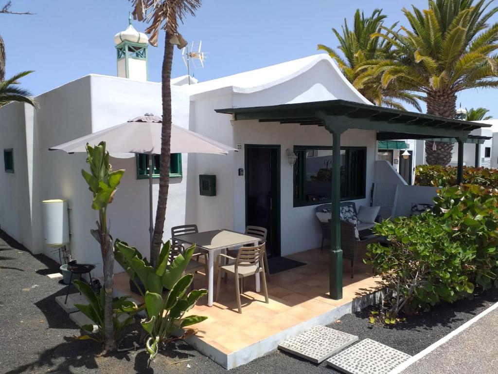 une terrasse avec une table et un parasol dans l'établissement Bungalow DALAI - Pool view- Good wifi, à Puerto del Carmen