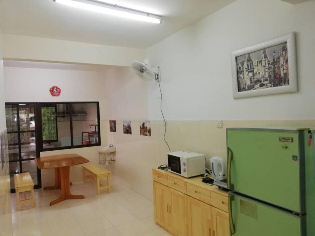 a kitchen with a green refrigerator and a table at Sweethome for travelers in Seremban