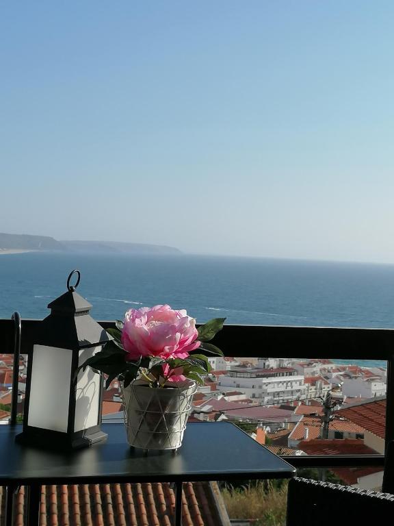 a vase with a flower on a table on a balcony at Flor do Mar in Nazaré