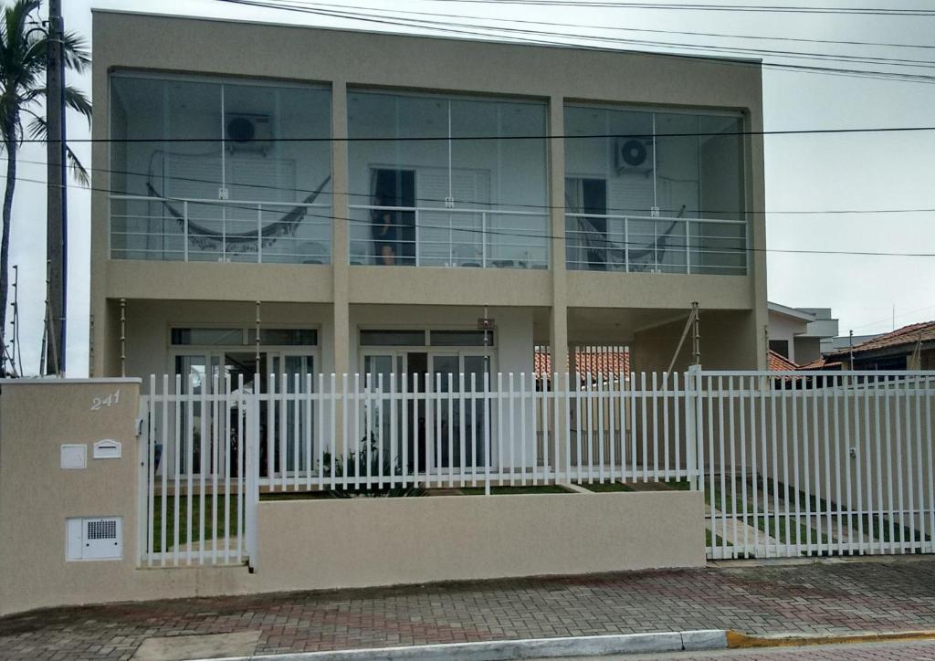 a building with a white fence in front of it at CASA - FRENTE PARA O MAR in Itanhaém