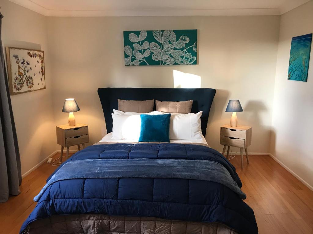 a bedroom with a large blue bed with two lamps at Villa Alessandra Rooms & Restaurant in Mount Tamborine