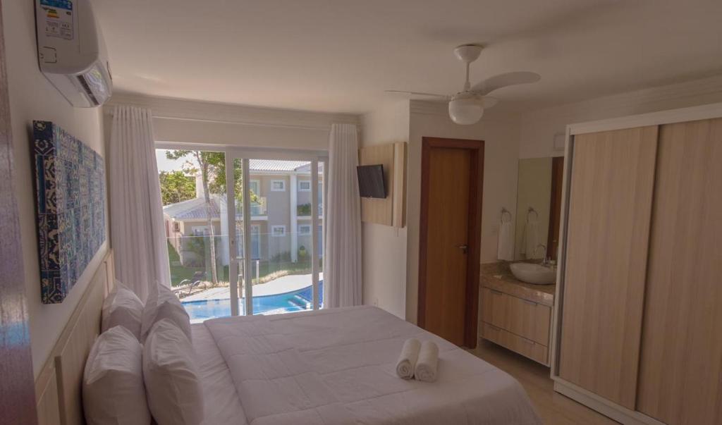 een slaapkamer met een bed en uitzicht op een zwembad bij Casa condominio fechado Arraial D’ajuda in Arraial d'Ajuda