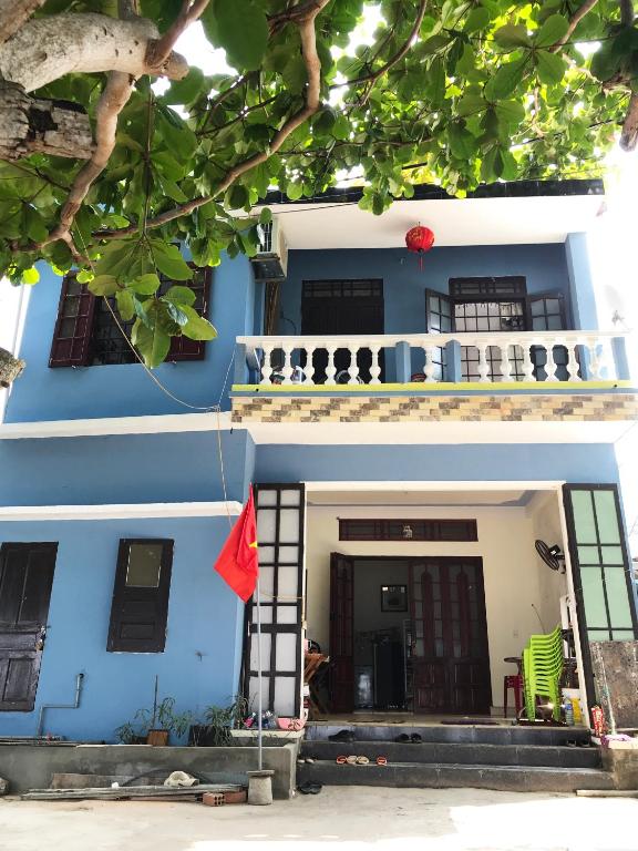 a blue house with a red flag in front of it at Tám Thọ homestay in Tân Hiệp