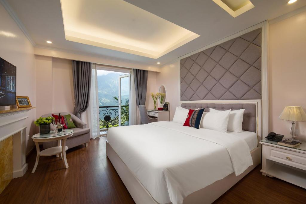 una camera da letto con un grande letto bianco e una finestra di Sapa Praha Hotel a Sa Pa