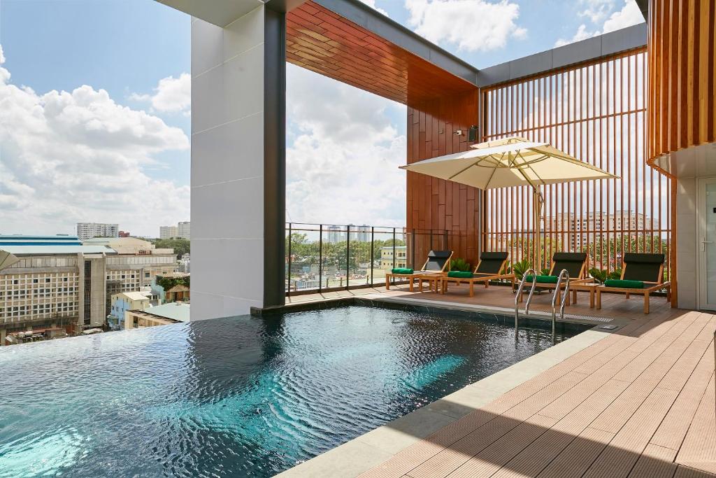 a pool on a building with chairs and an umbrella at Zazz Urban Ho Chi Minh in Ho Chi Minh City