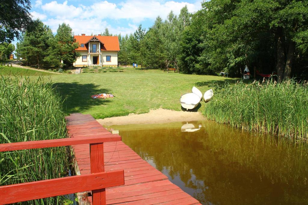 a wooden bridge over a body of water with a house at Bajkowe Mazury in Mikołajki