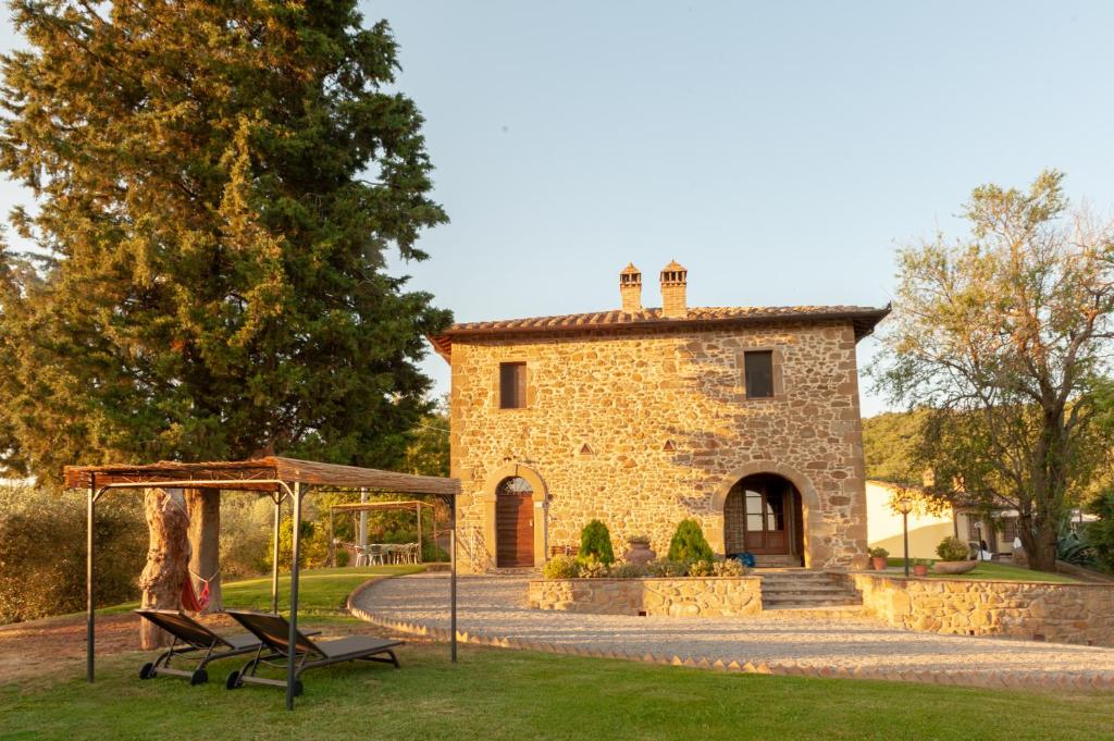 un edificio de piedra con un cenador frente a él en Agriturismo Poggio del Pero, en Panicale