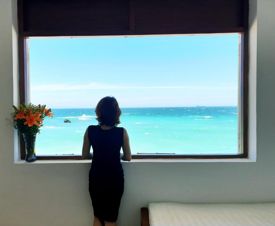 Una donna che guarda fuori da una finestra sull'oceano di Mũi Dinh Hotel a Phan Rang-Tháp Chàm