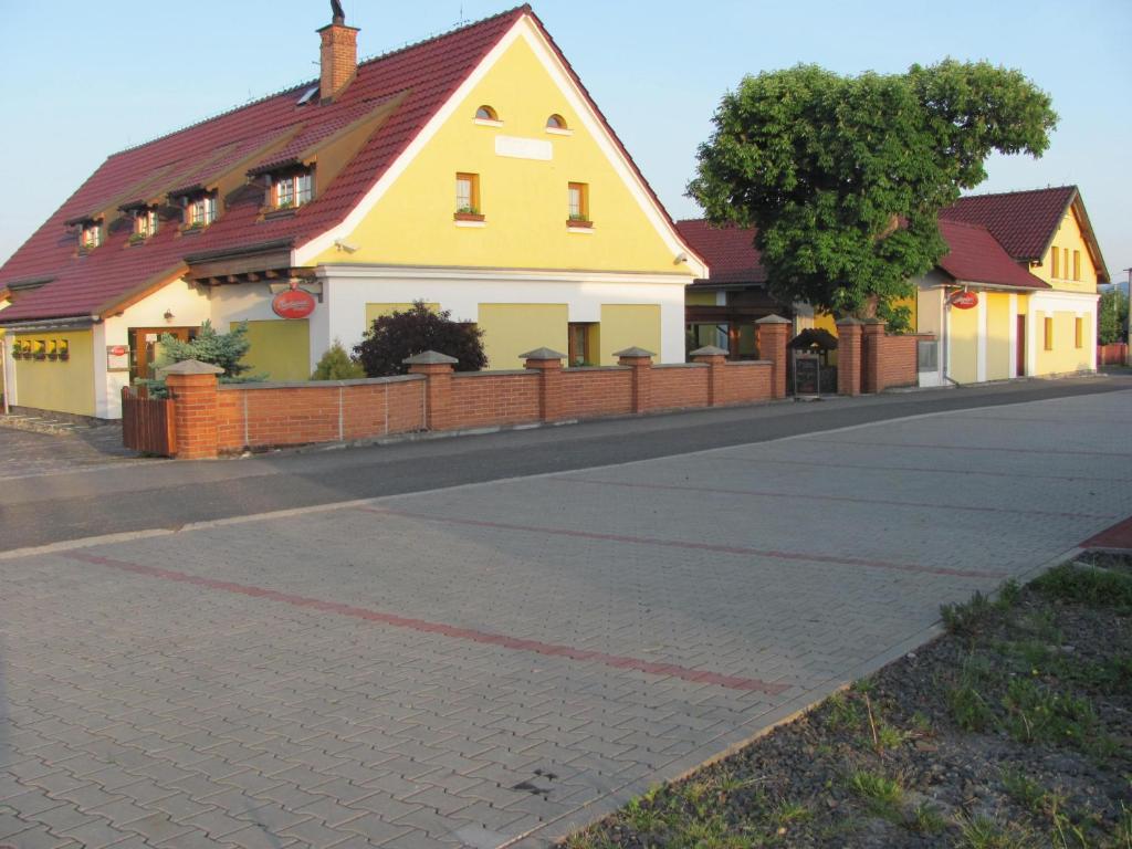 a yellow house with a red roof on a street at Šindlerův Dvůr in Krmelín