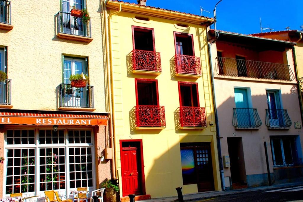 un edificio amarillo con puertas rojas y balcones en Naturaleza y aire puro en el Pirineo oriental en una bonita casa rural de piedra, en Prats-de-Mollo-la-Preste