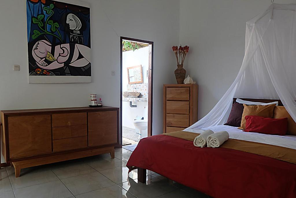 Ayu Hotel Karimunjawa في كاريمونجاوا: غرفة نوم بسرير وبطانية حمراء وخزانة