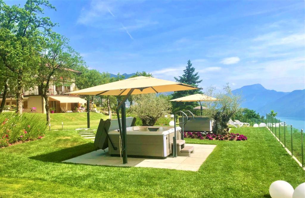 un patio con sombrilla, sillas y mesa en Villa delle Querce en Tremosine Sul Garda