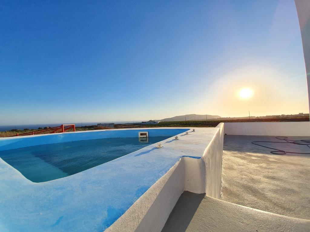 a swimming pool on the roof of a house with the sunset at Villa Therme Athena in Emporio Santorini
