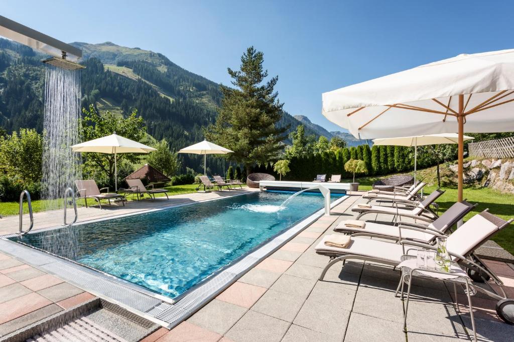 basen z leżakami i parasolami na patio w obiekcie Hotel Marten - Joker Card Partner w Saalbach Hinterglemm