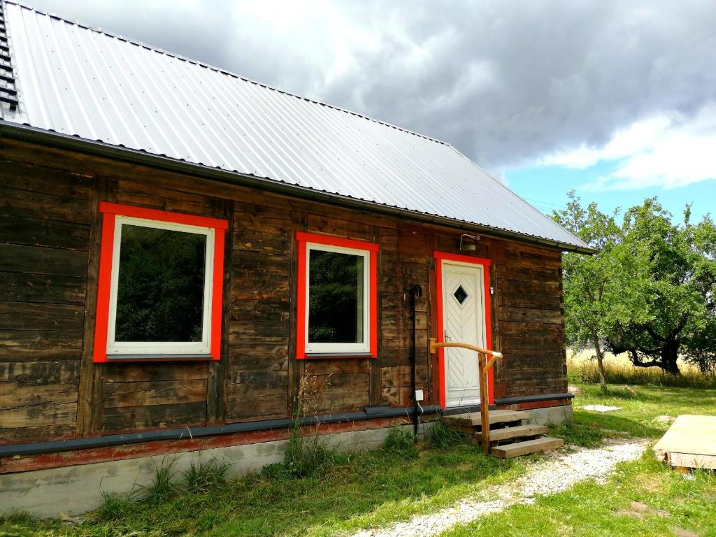 Casa de madera con ventanas rojas y puerta blanca en Dobry Dom, en Sejny