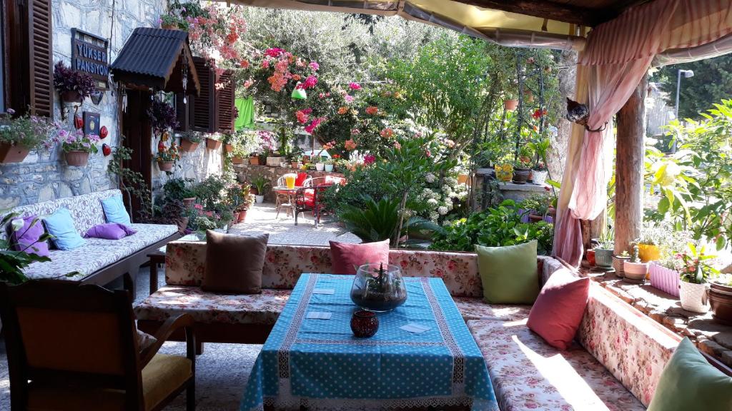 een patio met een tafel, stoelen en bloemen bij Yukser Pansiyon in Side