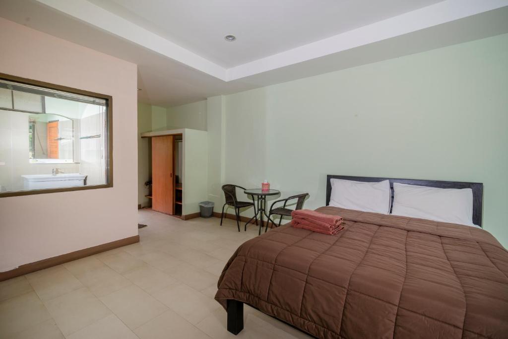 a bedroom with a bed and a table with chairs at Banlanna Hotel Lampang in Lampang