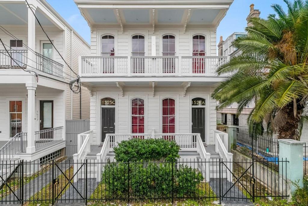 a white house with white railings and a palm tree at Fabulous Cottages with City Views in New Orleans