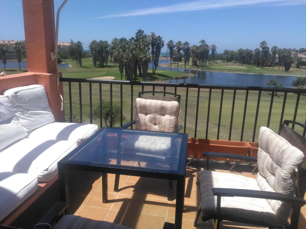 balcone con tavolo, sedie e vista su un campo da golf di Reina Sofía Apartment a Costa Ballena