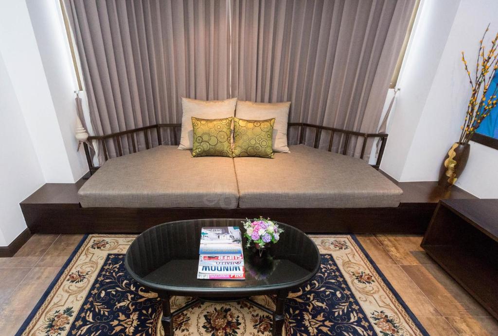 a small bed in a room with a table at The Grand Sathorn in Bangkok
