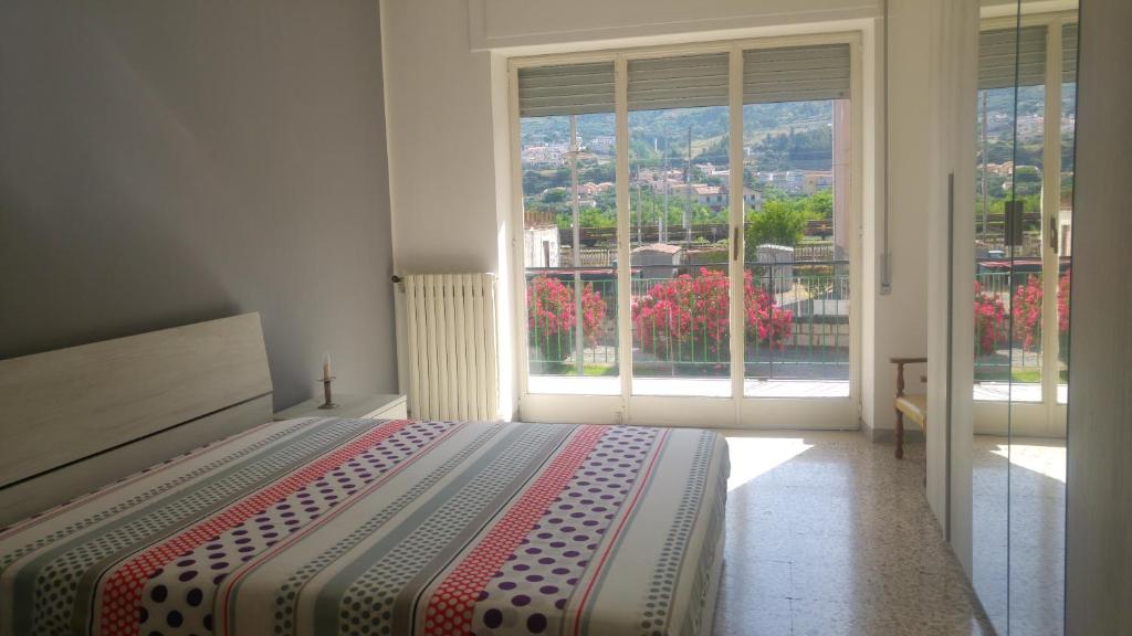 ein Schlafzimmer mit einem Bett und einem großen Fenster in der Unterkunft Appartamento Piave in Praia a Mare