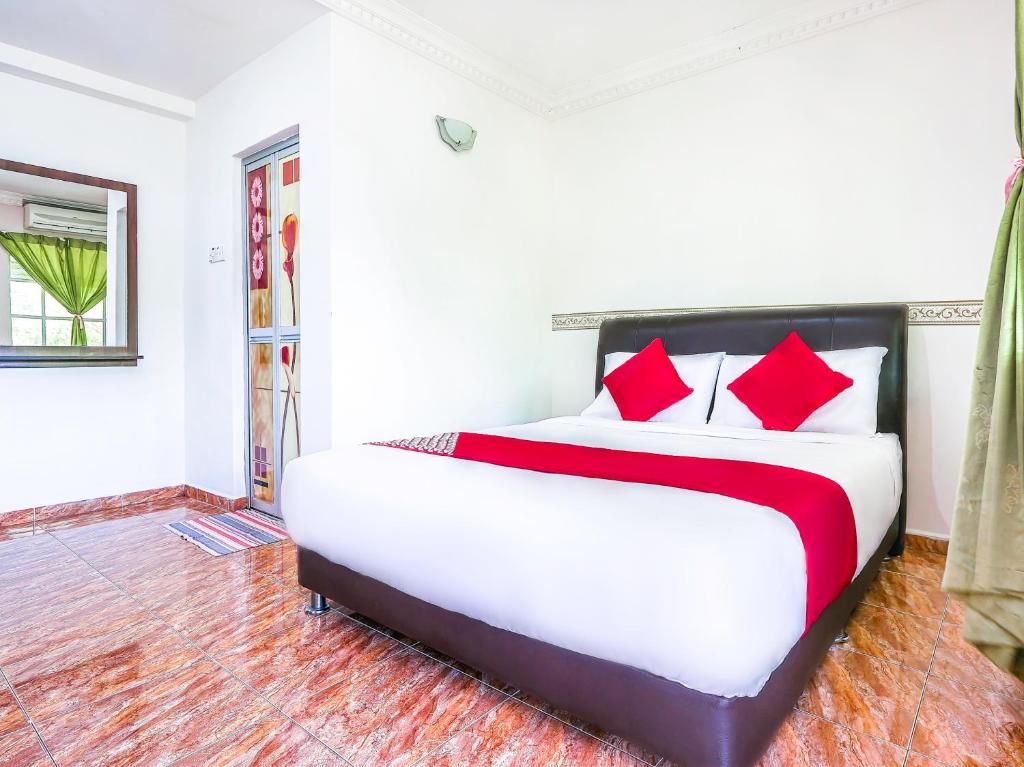 a bedroom with a large bed with red pillows at D' Anjung Inn in Tangkak