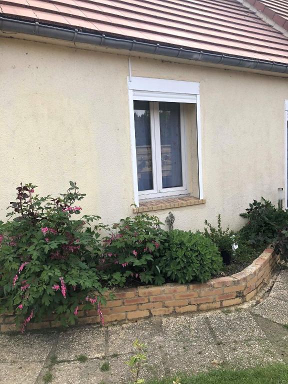 une fenêtre d'une maison avec des fleurs devant elle dans l'établissement La romance, à Le Breuil-en-Auge
