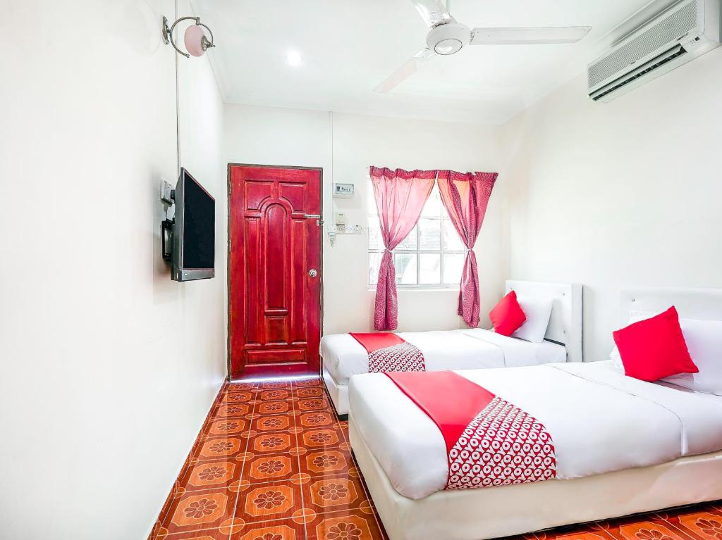 a room with two beds and a red door at D' Anjung Inn in Tangkak