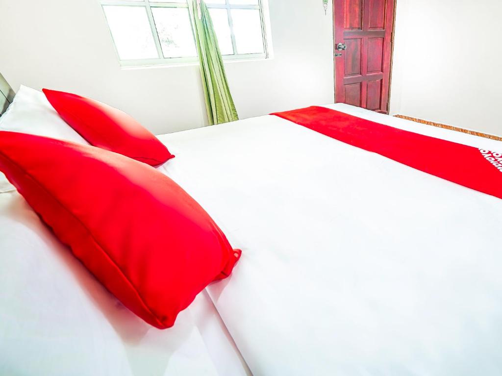 a bedroom with red pillows on a white bed at D' Anjung Inn in Tangkak