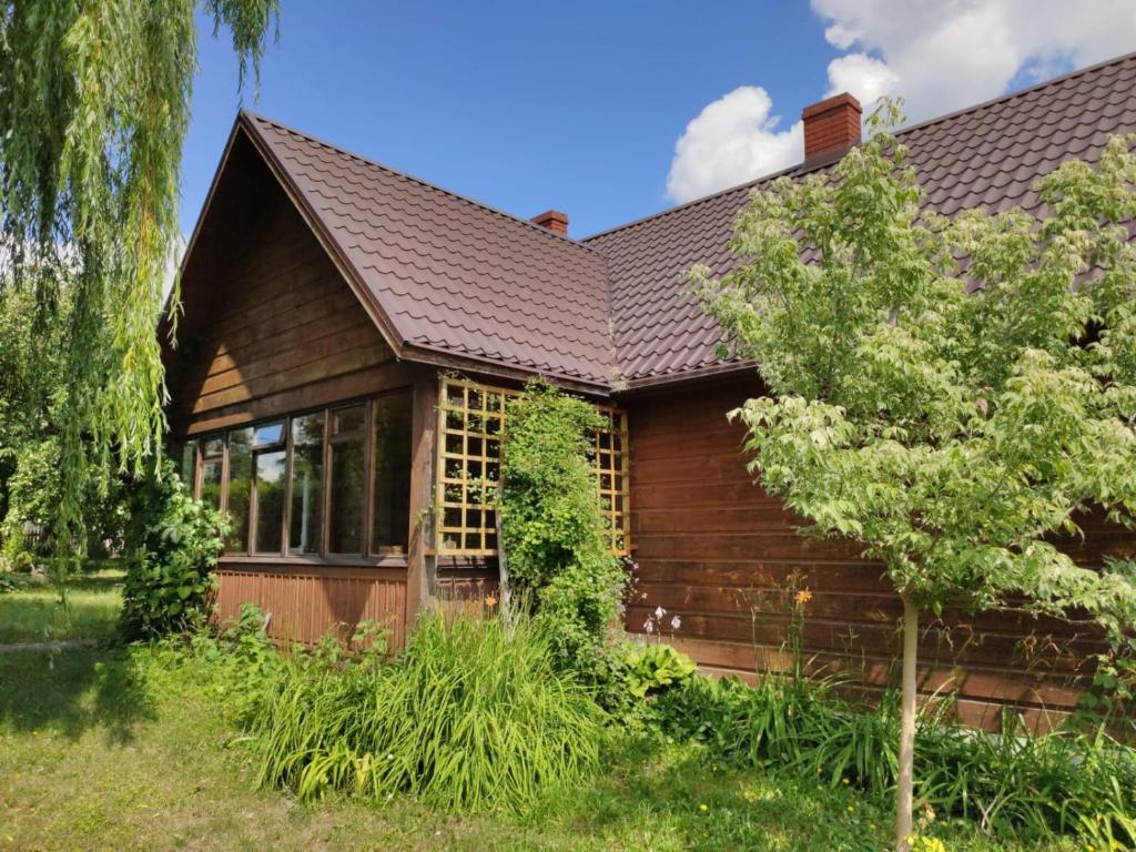 una casa de madera con un árbol delante en W Starym Sadzie en Białowieża
