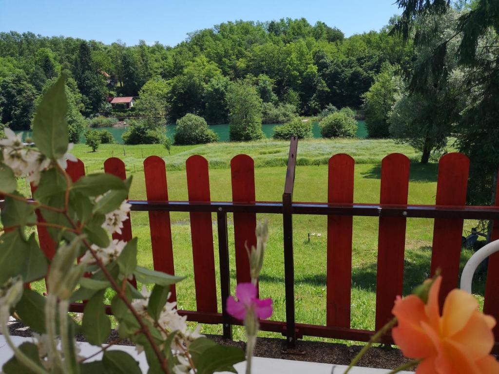 uma cerca vermelha com um campo ao fundo em Family & Friends apartments - Mrežnica em Duga Resa