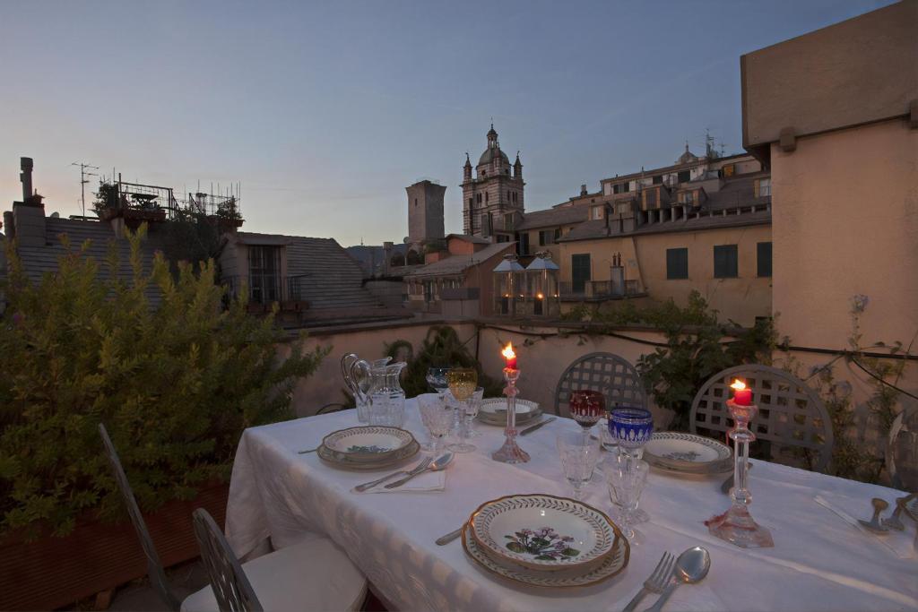 une table avec un chiffon de table blanc, des assiettes et des bougies dans l'établissement Sui tetti del centro di Genova by Wonderful Italy, à Gênes