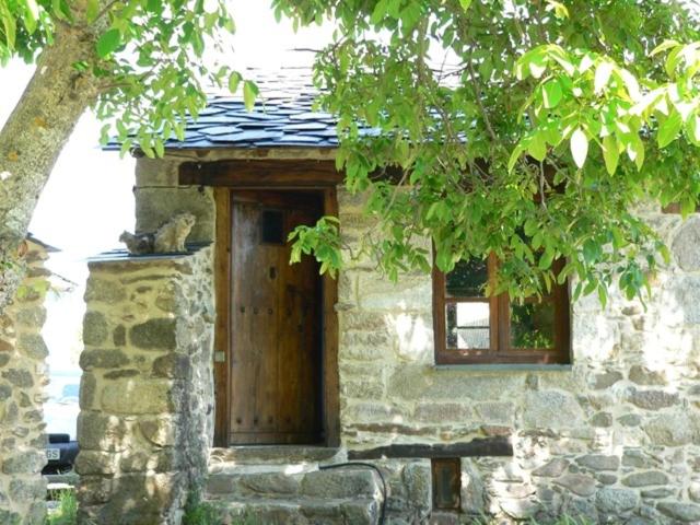 een stenen gebouw met een houten deur en een boom bij El Taller De La Seda in Avedillo de Sanabria