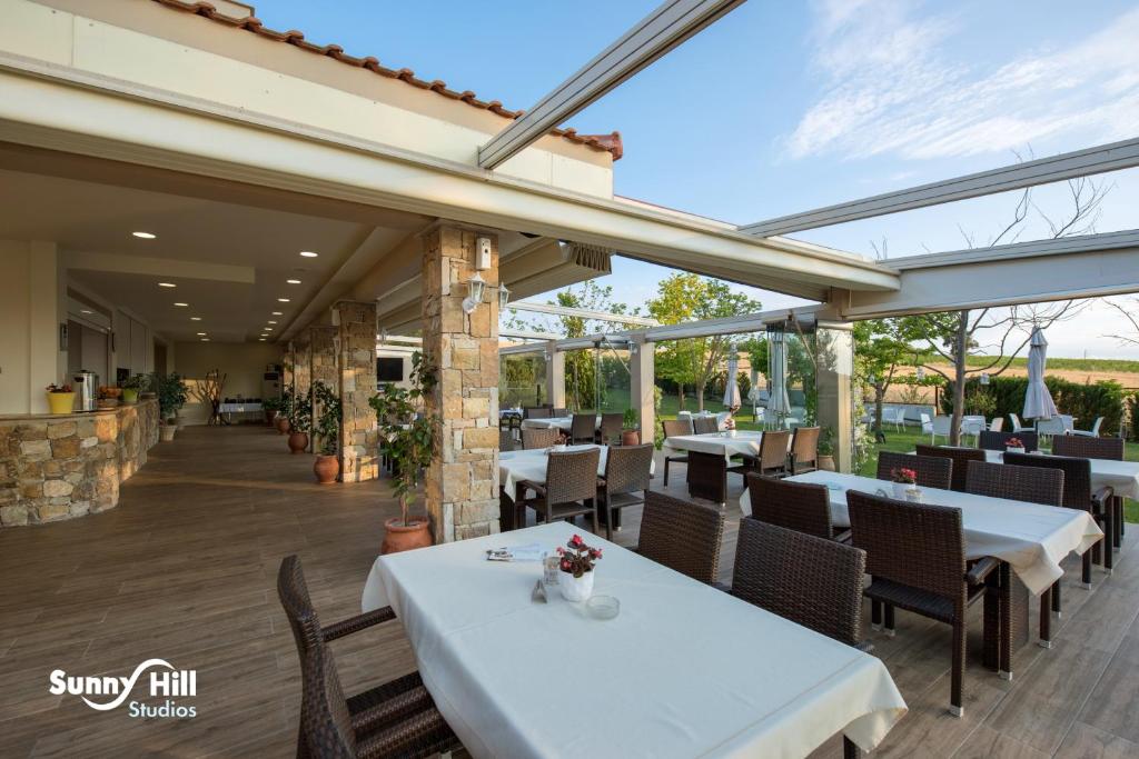 a restaurant with white tables and chairs and windows at Sunny Hill in Sani Beach