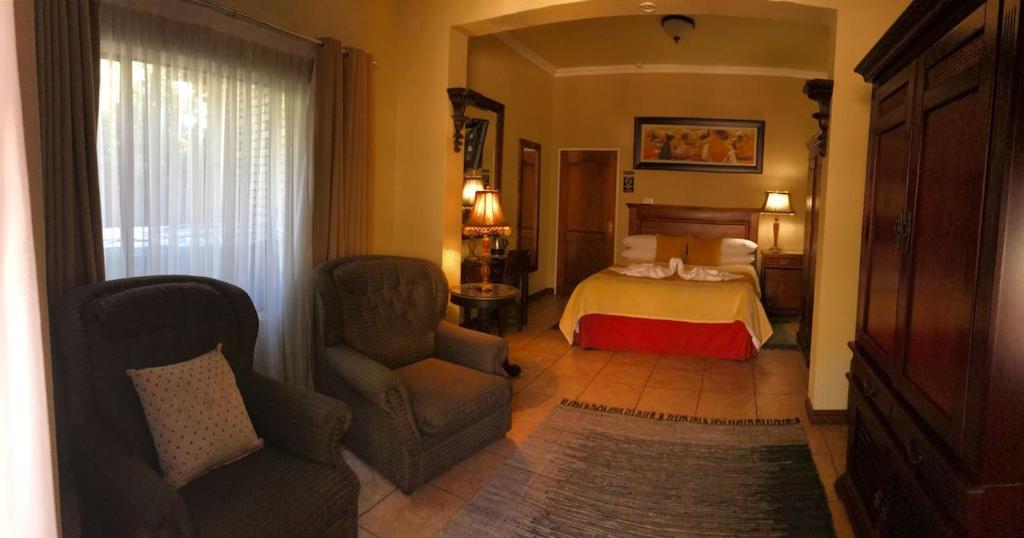 a hotel room with a bed and a chair at Le Cozmo Guesthouse in Johannesburg