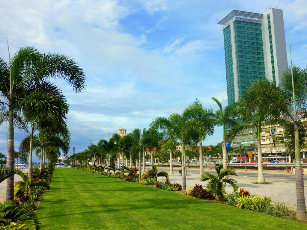 a park with palm trees and a tall building at Hotel Presidente Luanda in Luanda